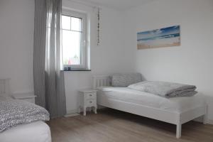 ボルンにあるFerienhaus Svea in Bornの白いベッドルーム(ベッド1台、窓付)
