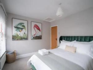 a bedroom with a large white bed with three pictures on the wall at Central Victorian terraced house Patio Garden - Pass the Keys in Cheltenham