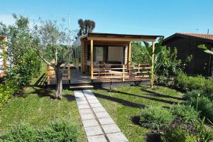 eine kleine Hütte mit einer Terrasse im Garten in der Unterkunft Le Dune Villaggio in Lido Di Fondi