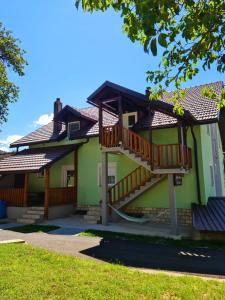 a green house with wooden stairs on it at Apartman Silvija in Otočac