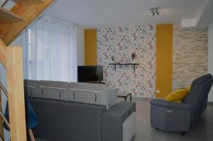 sala de estar con sofá, silla y TV en Les embruns, maison neuve près des plages, en Asnelles