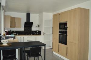 a kitchen with white cabinets and a black counter top at Les embruns, maison neuve près des plages in Asnelles