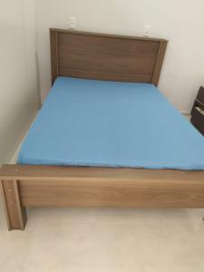 1 dormitorio con cama de madera con sábanas azules en SEU LAR en Machadinho