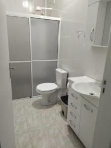 een witte badkamer met een toilet en een wastafel bij SEU LAR in Machadinho