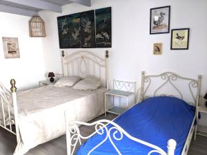 a bedroom with two white beds and a blue blanket at Le cabinet de curiosités in Aiguèze