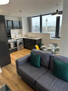 a living room with a couch and a table and a kitchen at Stunning City View Apartment by Central Stay in Liverpool
