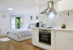 Una cocina blanca con una cama en una habitación en Studio proche Roland Garros, en Boulogne-Billancourt