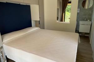 a large white bed in a bedroom with a mirror at Le Dune Villaggio in Lido Di Fondi