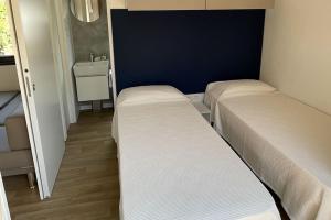 two beds in a small room with a sink at Le Dune Villaggio in Lido Di Fondi