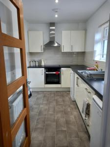 a kitchen with white cabinets and a tile floor at Penglais Lodge in Aberystwyth