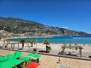 a beach with green umbrellas and people on the beach at Chez L's in Menton