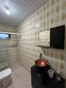 baño con lavabo y TV en la pared en Casa Cachoeira do bom Jesus, en Florianópolis