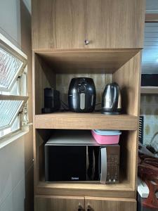a cupboard with a microwave and a coffee maker at Casa Cachoeira do bom Jesus in Florianópolis