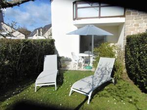 2 sillas y una mesa con sombrilla en un patio en Appartement 2 à 4 personnes à 50 m du port de St Jacques - Kolen, en Sarzeau