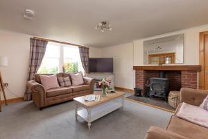 een woonkamer met een bank en een open haard bij Drumlanrig Mains Cottage in Thornhill