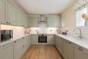una cocina blanca con armarios blancos y fregadero en Drumlanrig Mains Cottage en Thornhill