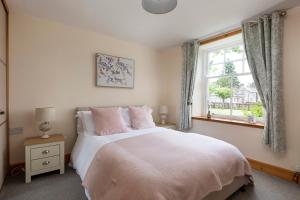 a bedroom with a large white bed with a window at Drumlanrig Mains Cottage in Thornhill