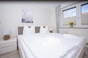 um quarto branco com uma grande cama branca com almofadas brancas em Haus Rügensonne, App 02 em Baabe