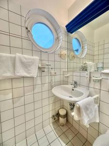 Baño de azulejos blancos con lavabo y espejo en Gästezimmer Weserblick, en Berne