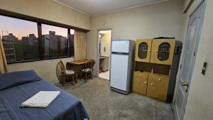 Habitación con cama, nevera y mesa. en Edificio Presidente en Mendoza