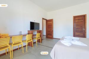 a room with a table and chairs and a television at Apto 100m da praia no Pontal de Maceió por Tactu in Maceio