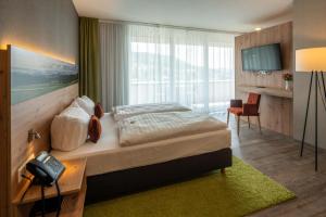 Schlafzimmer mit einem Bett, einem Schreibtisch und einem Telefon in der Unterkunft Hotel Schlossberg Wehingen in Wehingen