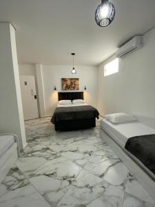 um quarto com 2 camas e piso em mármore em pousada fast sleep no Guarujá