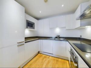 eine weiße Küche mit weißen Schränken und einem Waschbecken in der Unterkunft Homestay Room with stunning Thames river view in London