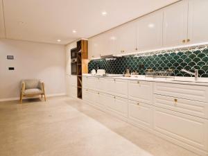 a kitchen with white cabinets and a chair at SHELL LIVING - Infinity Loft in Funchal