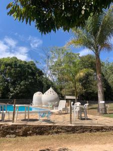 una piscina con alcune sedie, un tavolo e un albero di Pousada e Hostel Caminho de Santiago a Alto Paraíso de Goiás