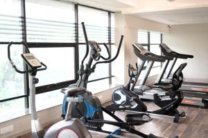 drie hometrainers in een sportschool met ramen bij Infinity Penthouse with Pool, Sauna, Gym in Rajkot