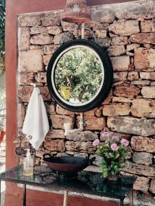a mirror hanging on a brick wall with a sink at Lalera stay in Chāndawāri