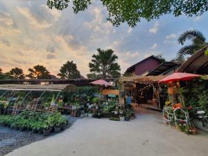 an outdoor market with flowers and plants in pots at บ้านนกฮูกอิงไม้ อิงมัจฉา in Ban Khlong Sai
