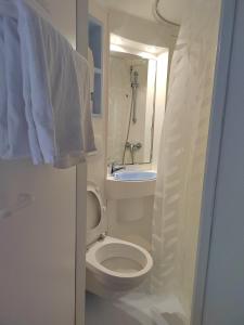 een witte badkamer met een toilet en een wastafel bij Alpha Hotel in Bouafle