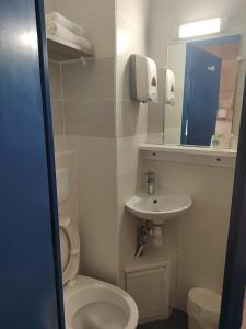 uma casa de banho com um WC, um lavatório e um espelho. em Alpha Hotel em Bouafle