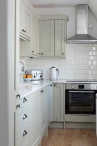 cocina blanca con armarios blancos y fogones en Stableyard Apartment: Drumlanrig Castle, en Thornhill