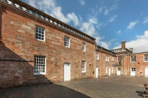 un gran edificio de ladrillo con puertas y ventanas blancas en Stableyard Apartment: Drumlanrig Castle, en Thornhill