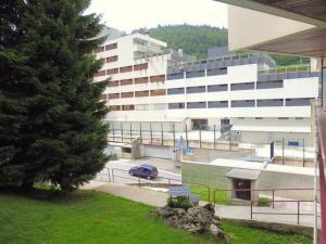 un grand bâtiment avec une voiture garée devant dans l'établissement Charmant Studio à Proximité des Pistes – 4 Pers., Balcon, Tout Équipé - FR-1-400-4, à Gourette