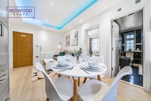 uma sala de jantar branca com uma mesa e cadeiras brancas em BRAND NEW, 1 Bed 1 Bath, Modern Town Center Apartment, FREE Parking, Netflix By REDWOOD STAYS em Aldershot