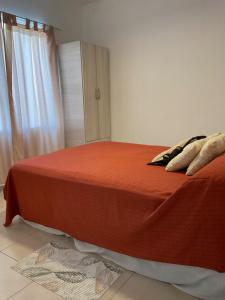 1 dormitorio con cama con sábanas de color naranja y ventana en Tres Reinas en Carmen de Patagones