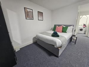 1 dormitorio con 1 cama con almohadas verdes y rojas en LiveStay-Studio Flat in Dalston en Londres