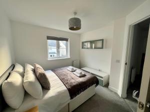 a bedroom with a bed with white pillows and a window at Beautiful 4-Bedroom House with Private Garden & Parking in Edinburgh