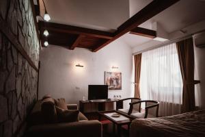 a room with a couch and a desk and a television at Popova Kula Hotel & Winery in Demir Kapija