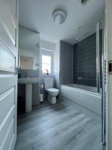 a bathroom with a tub and a toilet and a sink at Beautiful 4-Bedroom House with Private Garden & Parking in Edinburgh