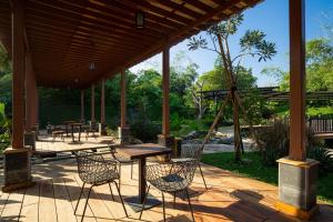 un patio con mesas y sillas en una terraza de madera en NIWA CANTING en Brumbung