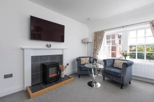 een woonkamer met 2 stoelen en een open haard bij Stableyard Studio: Drumlanrig Castle in Thornhill