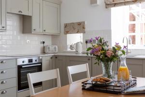Stableyard Studio: Drumlanrig Castle في ثورنهيل: مطبخ مع طاولة خشبية مع إناء من الزهور