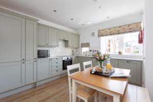 a kitchen with white cabinets and a wooden table at Stableyard Studio: Drumlanrig Castle in Thornhill