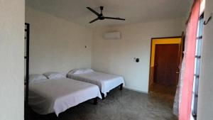 a room with two beds and a ceiling fan at Casa Calandria in Chicxulub