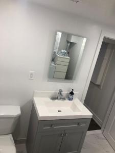 a white bathroom with a sink and a mirror at Home from Home! in Brampton